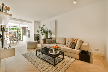 a living room with white walls and hardwood flooring, including a large coffee table in the center of the room