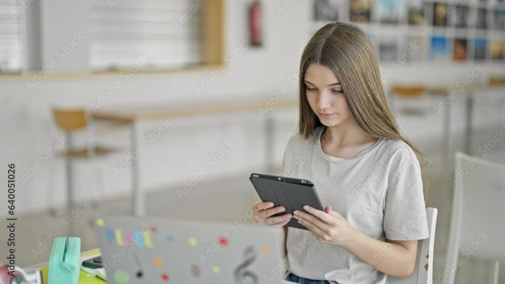 Sticker Young beautiful girl student using laptop and touchpad studying at library