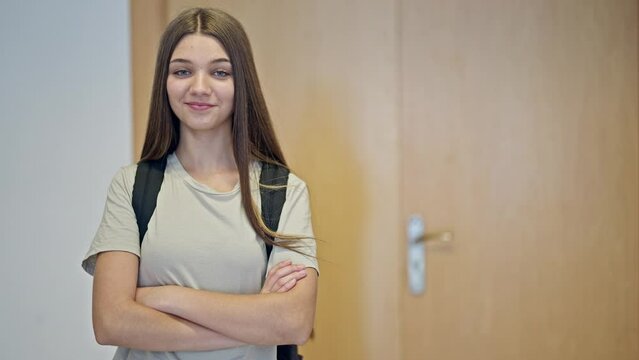 Young beautiful girl student wearing backpack standing with arms crossed gesture smiling at school