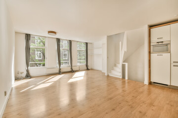 an empty living room with wood flooring and white appliances on the wall in the room is bright, sunny