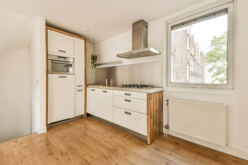 Fototapeta na wymiar a kitchen area with wood flooring and white cupboards on either side of the window looking out onto the street