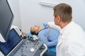Fototapeta na wymiar Adult woman having thyroid exam with ultrasound at doctor's office. Healthcare concept
