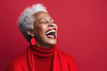 Smiling portrait of a african senior woman in a studio with a red background