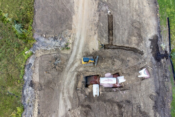 Dozer next to an open trench with two culverts ready for a connection juncture. 