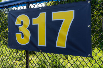 317 foot ft baseball field distance sign in yellow and black mounted on the black vinyl outfield...