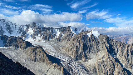 View of the snow-capped peaks of the Kyrgyz mountains. Rocks, glacier, blue sky and white clouds....