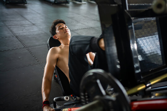Asian men athletes doing leg press exercises with machines to strengthen muscles for health care at the gym stadium