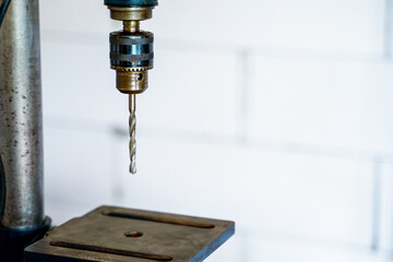 Old drilling machine with a metal drill close-up on a blurred light background