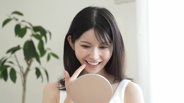 鏡を持ち歯を気にする日本人女性