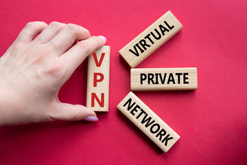 VPN - Virtual Private Network. Wooden cubes with word VPN. Businessman hand. Beautiful red...