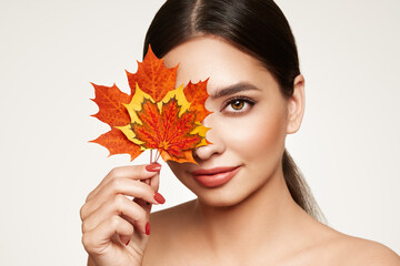 Portrait of beautiful young woman with autumn leafs. Healthy clean fresh skin natural make up...