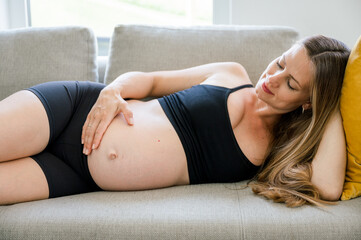 Obraz na płótnie Canvas Crop of pregnant woman lying on sofa