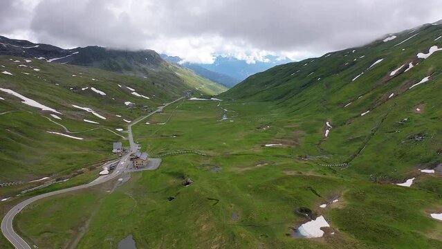 Drone footage, drone video, drone flight, aerial photo, flight at the mountain pass Kleiner San Bernardo, border station Italy and France, country road, Alps, snow, mountain panorama, fog, clouds