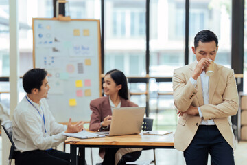 Portrait of happy and confident young man against background of his business team colleagues