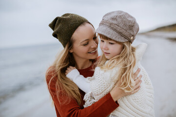 Mother and daughter walking on a beach during winter