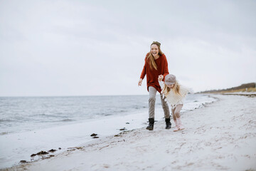 Mother and daughter walking on a beach during winter