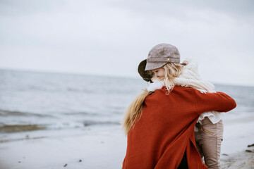 Mother and daughter walking on a beach during winter