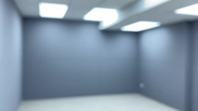 Blurred modern interior design of showroom with empty office room grey wall and white floor and light from ceiling
