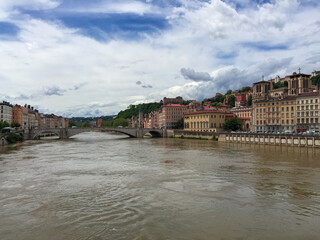 Fototapeta premium Scenic view of River Saone with Bonaparte Bridge and historical old town of Lyon, Auvergne-Rhone-Alpes, France, Europe. City walking tour on a cloudy day in summer. City tourism and landmarks