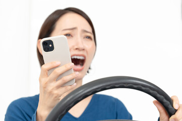 スマホを見ながら驚く女性ドライバー