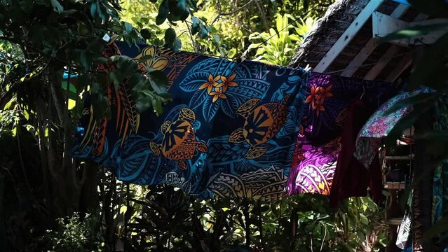 Traditionally dyed and printed tropical sarong with vivid turtle and flower theme on a line blowing in the wind
