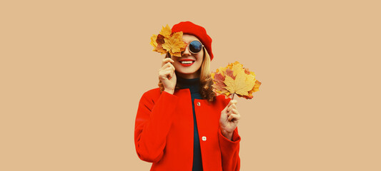 Autumn color style outfit, portrait of beautiful smiling young woman with yellow maple leaves...