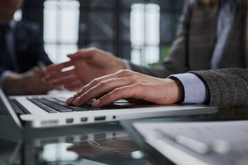 man's hands typing on laptop keyboard in interior