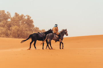 Moroccan berber man with horses through the sahara desert in Merzouga, Morocco - obrazy, fototapety, plakaty