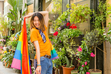 Asian gay man playing with a lgbt rainbow flag outdoors