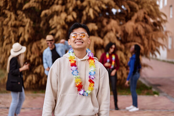 Asian man smiling while celebrating a party with friends outdoors. Party and celebration concept.