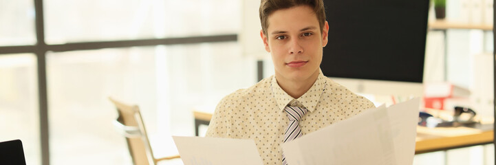 The young man watches documents in the office, close-up