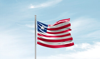 Liberia national flag waving in beautiful sky. The symbol of the state on wavy silk fabric.