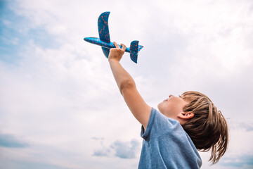 Child dream to fly. Happy boy child runs with toy plane. Boy kid playing aviator. Kid dream of becoming an astronaut. Child flight dream concept - obrazy, fototapety, plakaty