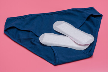 Białe bawełniane wkładki higieniczne i kobiece majtki na różowym tle - obrazy, fototapety, plakaty