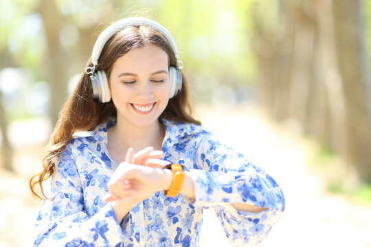 Happy woman with headphone checking smartwatch