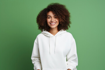 Young smiling latin woman wearing blank white hoodie isolated on a green background. AI