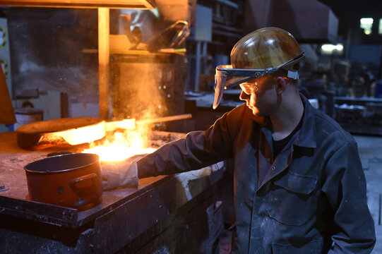 young worker in protective clothing at work at the blast furnace in an iron foundry