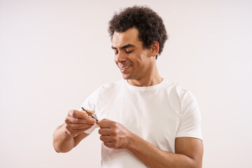 Handsome mixed race adult man is cutting his fingernails.