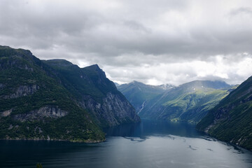 Fototapeta premium Enchanting beauty of Geirangerfjord, stunning fjord in Norway. Fjord is surrounded by majestic mountains, covered with lush green trees, creating picturesque landscape