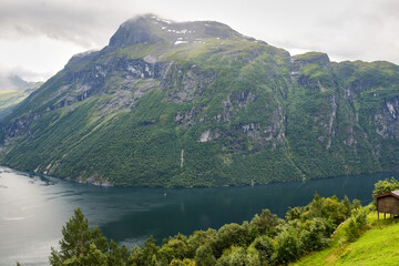 Obraz premium Geirangerfjord in Norway. Fjord is surrounded by majestic mountains, covered with lush green trees, creating picturesque landscape