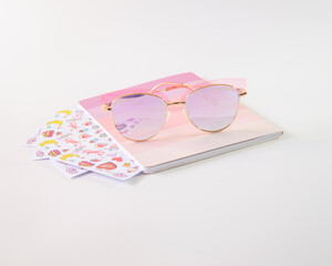 Libreta de color rosa con anteojos rosas y boligrafo rosas junto a etiquetas pegables de colores