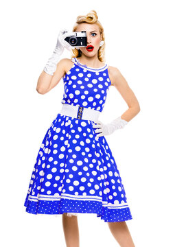 Full body photo of young woman with no-name old film camera, taking picture, wear in pin up blue dress. Beauty blond model posing in retro fashion vintage studio ad concept, isolated white background.