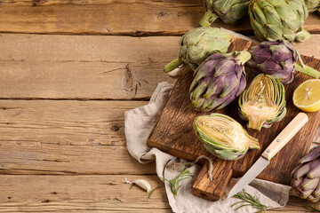 Green and purple artichokes on old wooden table, copy space