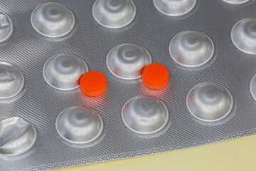 Red pills lie on foil blister pack close-up
