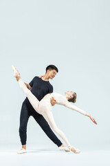 Dance Couple of Asian Young Man and Caucasian Woman Performing As Ballet Dancers Over Grey in Studio During Suppots As Classical Dance With Choreography Elements © danmorgan12