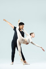 Dance Couple of Asian Young Man and Caucasian Woman Performing As Ballet Dancers Over Grey in Studio During Suppots As Classical Dance With Choreography Elements © danmorgan12