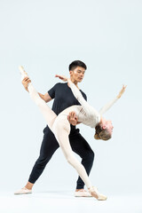 Couple of Asian Young Man and Caucasian Woman Performing As Ballet Dancers Over Grey in Studio During Suppots As Classical Dance With Choreography Elements © danmorgan12