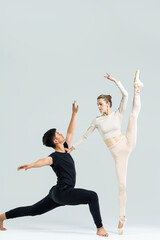 Couple of Asian Young Man and Caucasian Woman As Ballet Dancers Over Grey in Studio During Suppots As Classical Dance With Choreography Elements © danmorgan12
