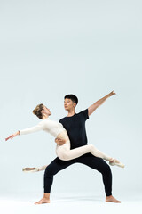 Ballet Concepts. Asian Young Man and Caucasian Woman Performing As Ballet Dancers Over Grey Studio Background Doing Suppots As Classical Dance Aesthetics With Choreography Art © danmorgan12