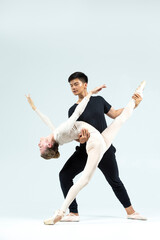Couple of Asian Young Man and Caucasian Woman Performing As Ballet Dancers Over Grey in Studio During Suppots As Classical Dance With Choreography Elements © danmorgan12